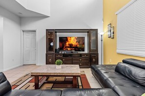 Ein Wohnzimmer mit Kamin, einer Couch, einem Couchtisch und einem Fernseher.
