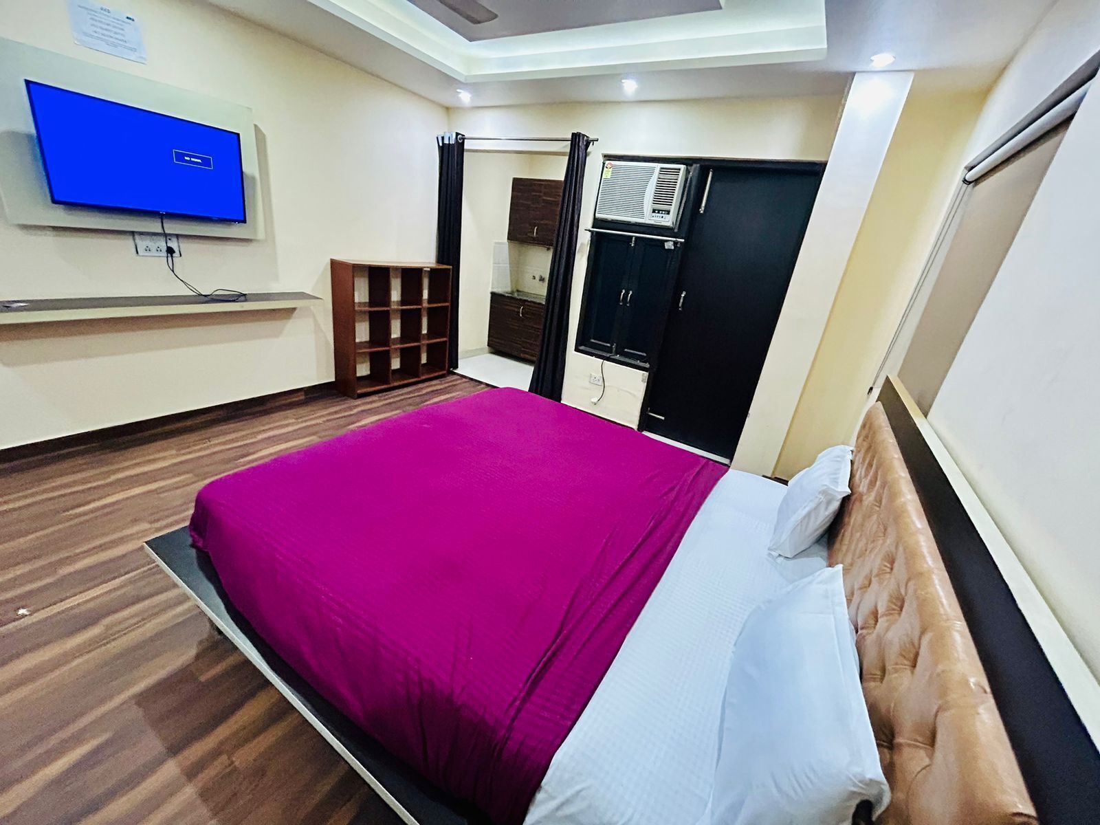 Une chambre d’hôtel équipée d’un lit, d’un téléviseur fixé au mur, d’une armoire et d’un appareil de climatisation.