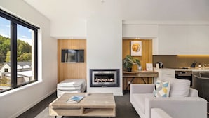 Ein modernes Wohnzimmer mit Kamin, Fernseher und Küchenzeile.