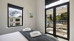 Ein Schlafzimmer mit Bett, Fenster mit Bergblick und Balkon mit Sitzgelegenheit.