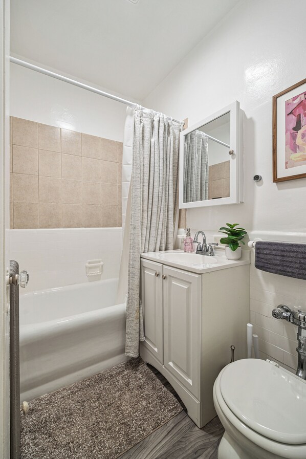 A bathroom with a bathtub, a sink, a toilet, and a mirror.