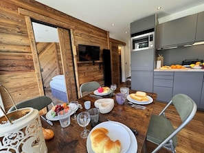 A dining area with a wooden table set for a meal, a kitchen with modern appliances, and a cozy interior design. - 3rd floor, balcony, tv, ski locker, 26m², Vars (Vars)