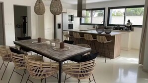 Una cocina moderna con una isla central, armarios blancos y un ventanal amplio.