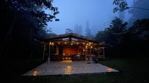 A covered outdoor area with a tiled floor, surrounded by trees.