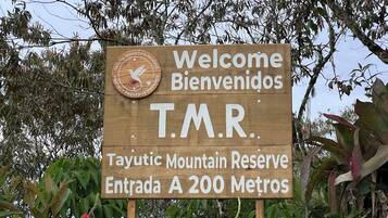 Ein hölzernes Willkommensschild für das Tayutic Mountain Reserve mit einem Vogel-Logo und der Aufschrift, Besucher willkommen zu heißen.