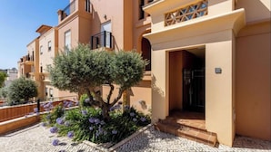A residential building with a tiled patio, a tree, and purple flowers. - Apartamento amplo no Baía da Luz – férias perfeitas para famílias na (Lagos)