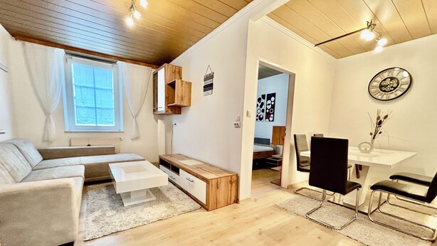 Un salon moderne et bien éclairé, avec un canapé, une table basse et un coin repas.