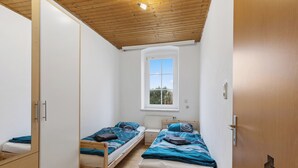 Une chambre avec deux lits simples, une fenêtre et un plafond en bois.