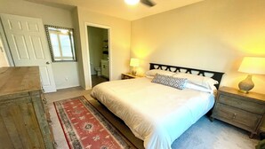 Ein Schlafzimmer mit Bett, Nachttischen, einem Schminktisch und einem Deckenventilator.