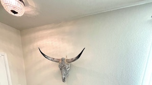 Ein Zimmer mit einer Bank, einem Wanddekor, einem kleinen Tisch mit einer Pflanze und einem gemusterten Teppich.