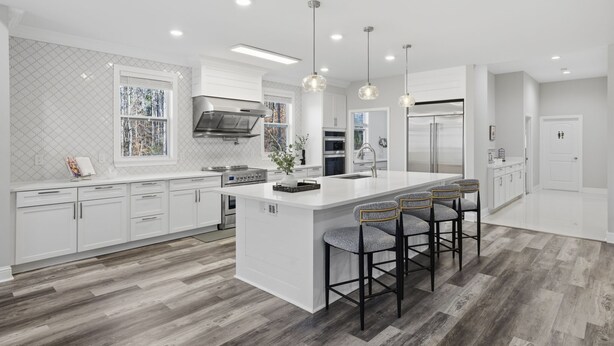 A modern kitchen with white cabinetry, a large island with bar stools, and a stainless steel range hood. - Luxe Retreat w/ Spa Sleeps 25 Designed For Groups (Charlotte)