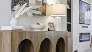 A wooden console table with books, a vase with pampas grass, a bowl, and a framed picture. - Luxe Retreat w/ Spa Sleeps 25 Designed For Groups (Charlotte)