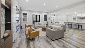 A spacious living room with a fireplace, a kitchen with a bar, and a dining area. - Luxe Retreat w/ Spa Sleeps 25 Designed For Groups (Charlotte)