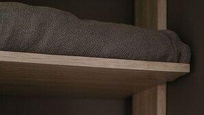 A wooden shelf with two rolled towels, one dark and one olive green.