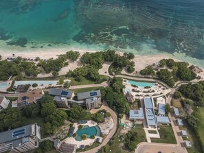 Una vista aerea di un resort con diversi edifici, una piscina e una spiaggia.