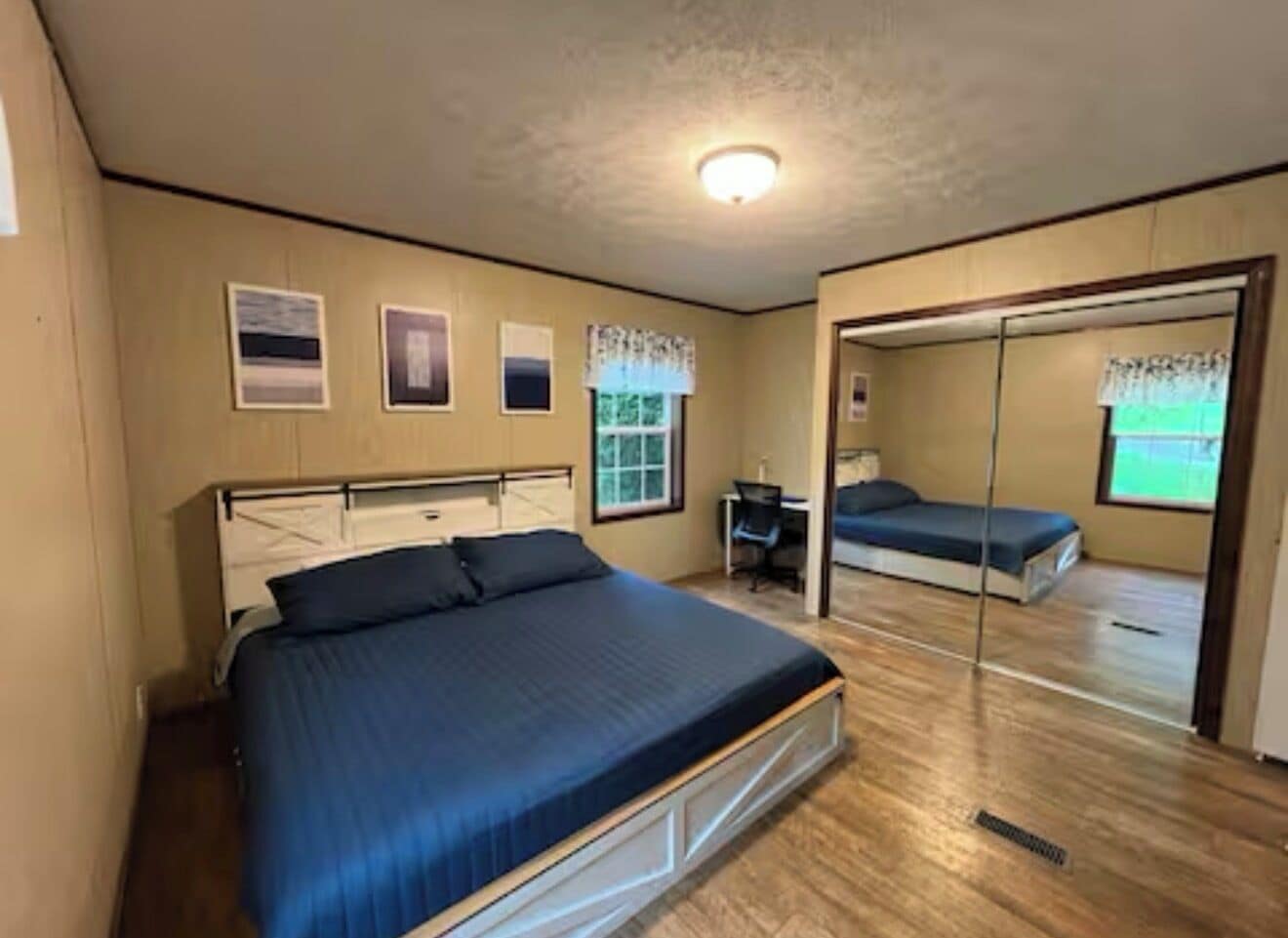 Een slaapkamer met een bed, een bureau en een spiegel.