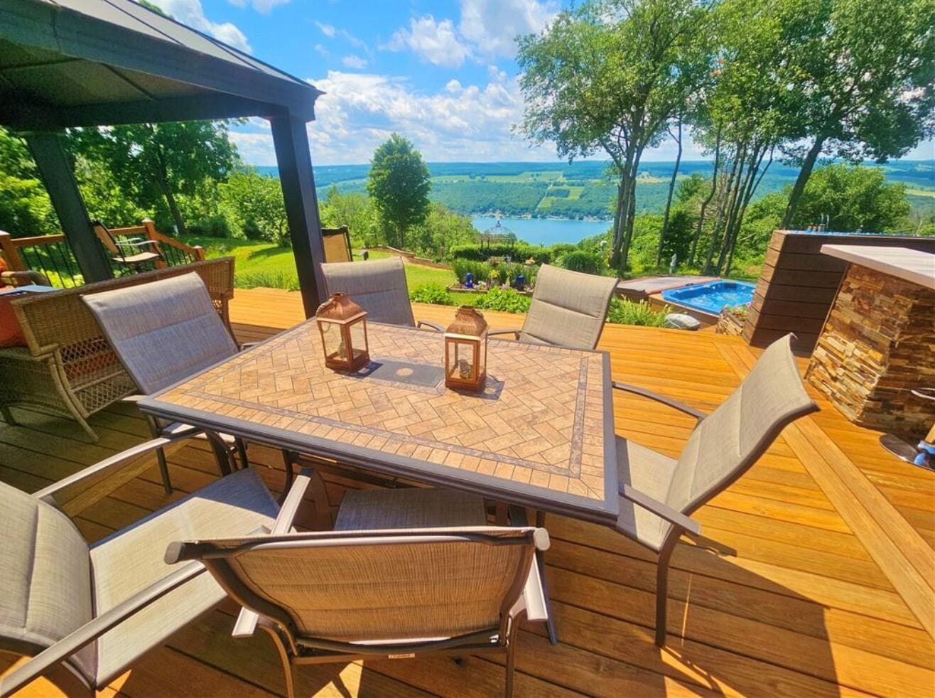 Une terrasse en bois avec une table et des chaises, offrant une vue sur un paysage magnifique.