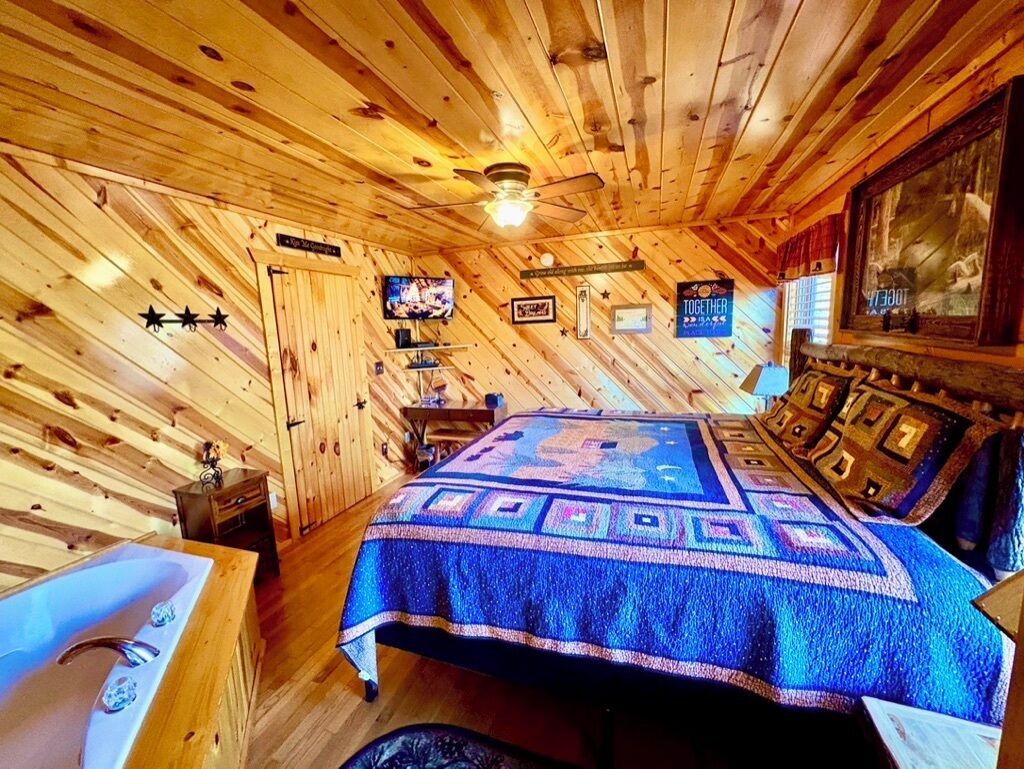 Une chambre dans un chalet en bois, équipée d’un lit, d’une télévision et d’un lavabo.