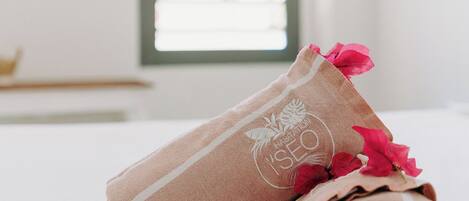 Une serviette soigneusement pliée, ornée d’un logo, posée sur une surface blanche parsemée de pétales de rose.