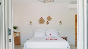 A neatly arranged bedroom with a large bed, bedside tables, and a wall-mounted light fixture. - Habitation I'SEO Adult Only (Sainte-Anne)