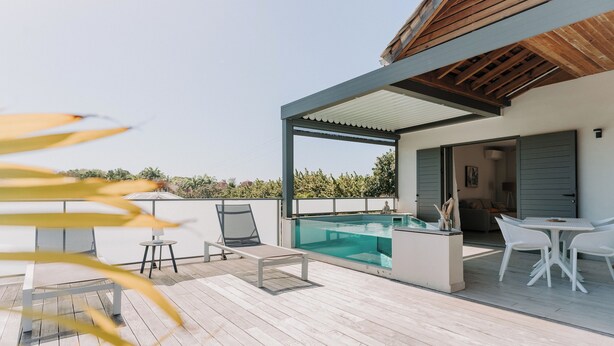 A modern outdoor deck with a pool, lounge chairs, and a dining area. - Habitation I'SEO Adult Only (Sainte-Anne)
