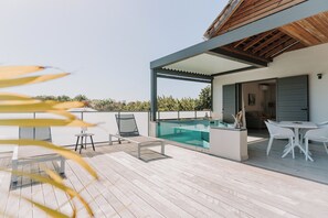 Una terraza moderna al aire libre con piscina, sillas de descanso y zona de comedor.