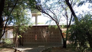 A brick building with a small window and a red and white striped sign. - Abril (Cafayate)