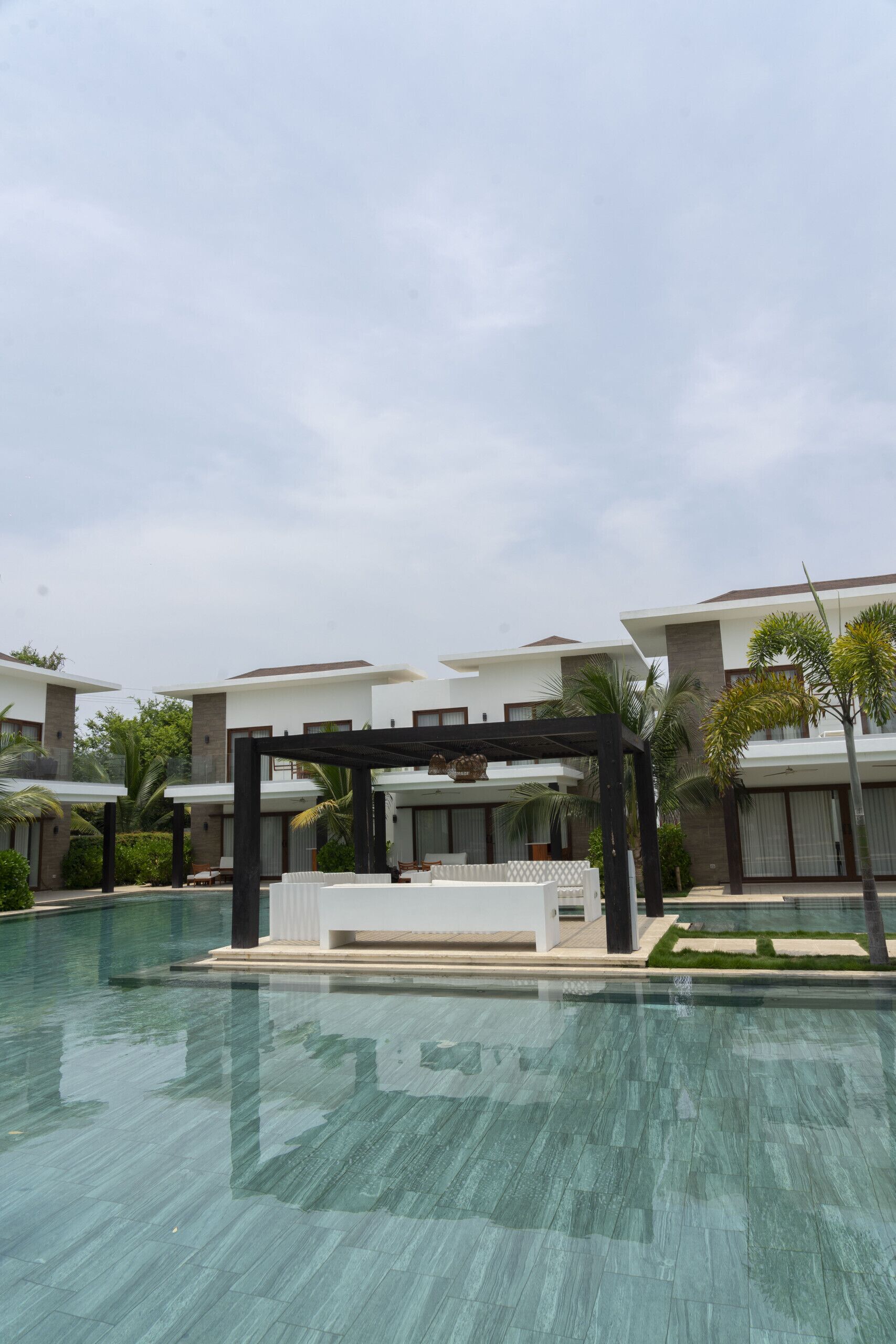 A modern hotel with a swimming pool, outdoor seating, and a covered area.