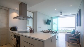 Et moderne køkken med en central ø, et spiseområde med bord og stole, samt et stort vindue med udsigt.