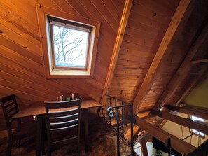 A wooden interior with a window, a table, and chairs. - Swiss Miss Pet-Friendly A-Frame only 6 Minutes from downtown Ellicottville! (Little Valley)
