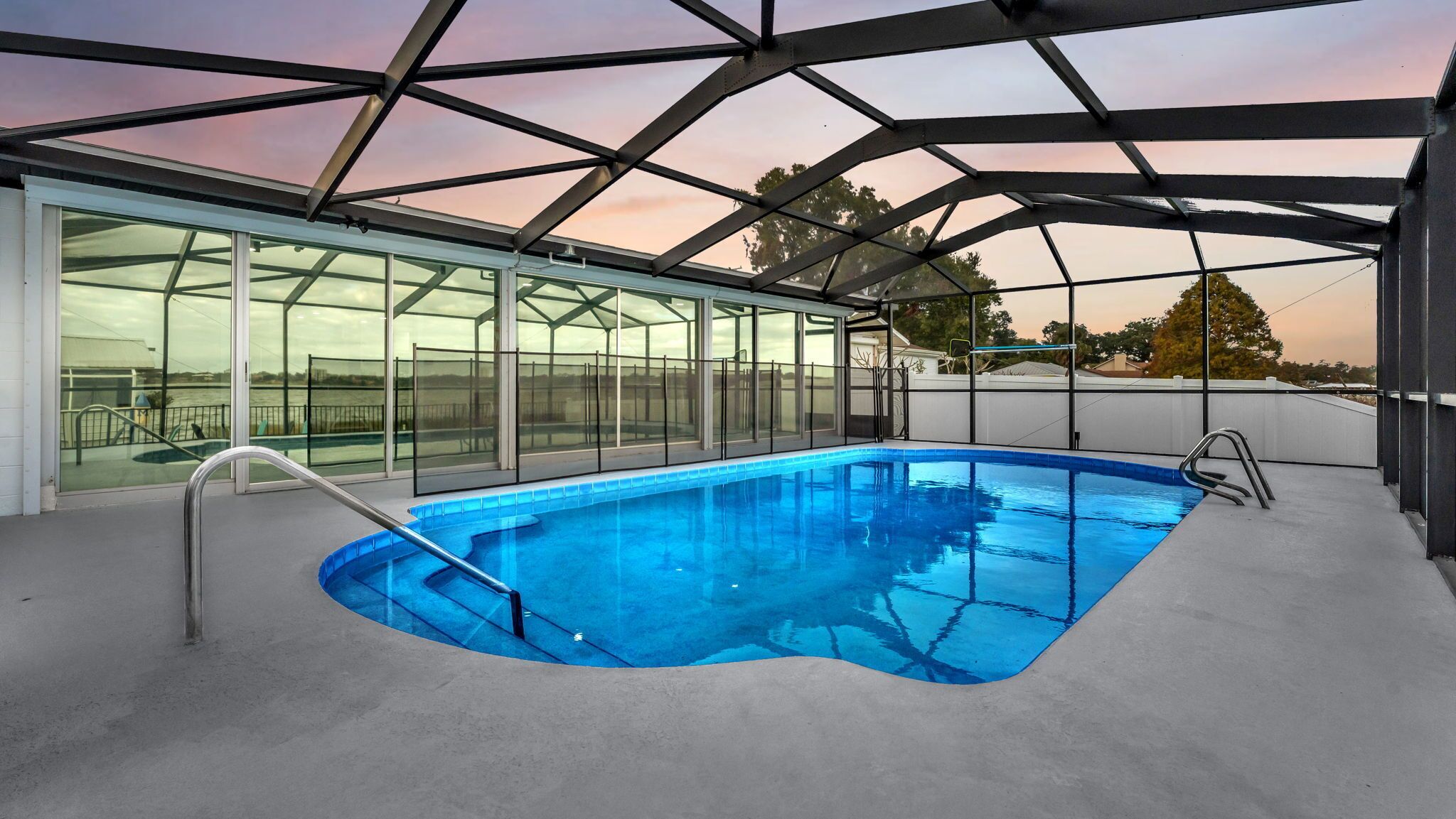 Une piscine intérieure moderne avec des murs en verre et une structure de toit en métal.
