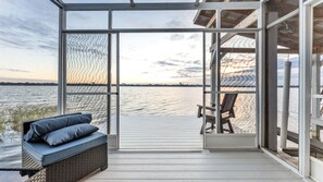 Una terrazza coperta con vista sull'acqua, un'area salotto con cuscini e una poltrona.