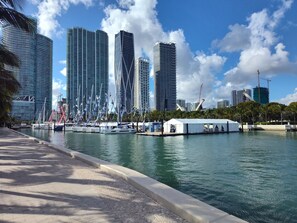 A waterfront view with modern high-rise buildings, a marina with boats, and a white tented area. - Cozy Cottage in Poinsettia Heights - Private, Stylish, and Minutes to Las Olas (Fort Lauderdale)