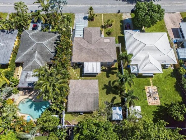 An aerial view of a residential area with multiple houses, a swimming pool, and palm trees. - Cozy Cottage in Poinsettia Heights - Private, Stylish, and Minutes to Las Olas (Fort Lauderdale)