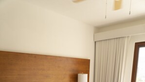 A large bed with a wooden headboard, a bedside table with a lamp, and a window with curtains. - Pool Entry 7 Guests 2 Bedrooms (Taxisco)