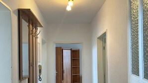 Un couloir avec une armoire en bois, un tapis noir et une porte sur laquelle est apposé un panneau «interdiction de fumer».