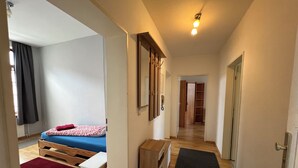 Une chambre d’hôtel moderne équipée d’un lit, d’un bureau, d’une armoire et d’un couloir menant à une autre pièce.