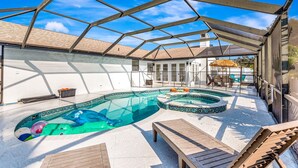 A covered outdoor swimming pool with a hexagonal roof structure, surrounded by a white building with a tiled roof. - Tropical Oasis with Pool, Spa, Putting Green & Game Room (Bradenton)