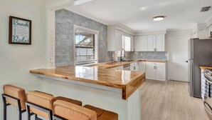 A modern kitchen with a central island, white cabinets, and a stone backsplash. - Tropical Oasis with Pool, Spa, Putting Green & Game Room (Bradenton)