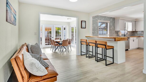 A modern living room with a leather sofa, a dining area with chairs, and a kitchen with a bar. - Tropical Oasis with Pool, Spa, Putting Green & Game Room (Bradenton)
