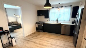 Een moderne keuken met een centraal eiland, zwarte kastjes en een roestvrijstalen koelkast.