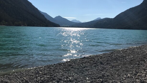 Un lac aux rives rocheuses, avec des montagnes en arrière-plan.