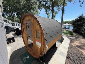 Une structure en bois en forme de tonneau, dotée d’une porte, d’un panneau d’avertissement et d  ’un support en métal.