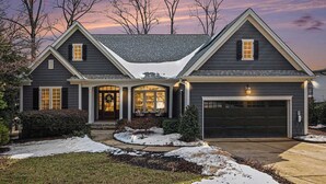 A two-story house with a dark gray exterior, a front porch with a covered entryway, and a garage. - New! Lakefront-Sleeps 14-Hot Tub-Putting Green (Denver)
