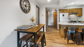 Una cocina moderna con armarios de madera, una isla integrada con taburetes de bar y un reloj montado en la pared.