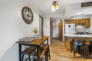 Eine moderne Küche mit Holzausstattung, einer integrierten Kücheninsel mit Barhocker und einer Wanduhr.