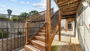 Una escalera de madera que conduce a un espacio exterior cubierto con barandilla metálica.