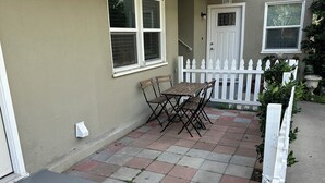 Un patio con tavolo e sedie, un recinto in legno bianco e una porta con il numero 239.
