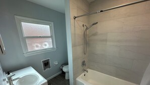 Un bagno con vasca, lavabo, finestra e doccia.