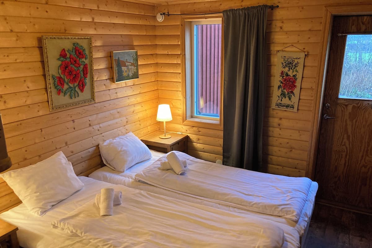 Acogedora habitación tipo cabaña con dos camas, una ventana con cortinas, una lámpara y adornos en la pared.